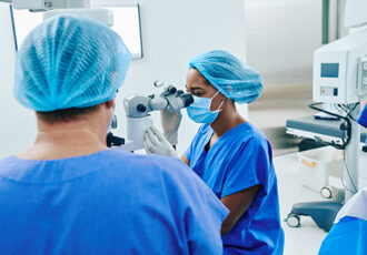 Young female Black surgeon getting ready for laser vision correction with usage of modern equipment